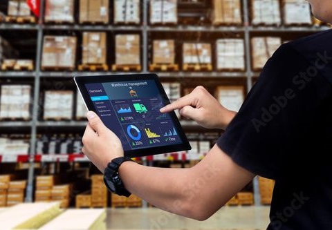 Man holding an IPAD in a freight warehouse