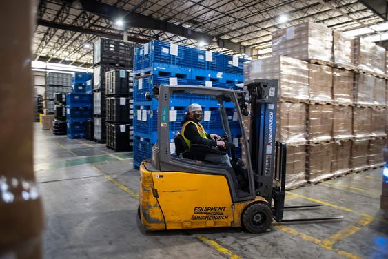 Man driving a yellow forklift inside a warehouse